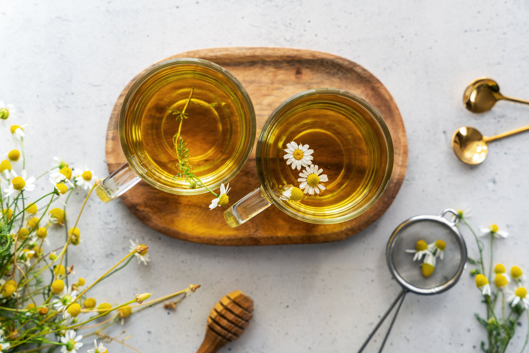 2 Glastassen mit Kräutertee auf einem Holztablett (Draufsicht)